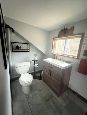 Een kleine badkamer met toilet, wastafel en raam.