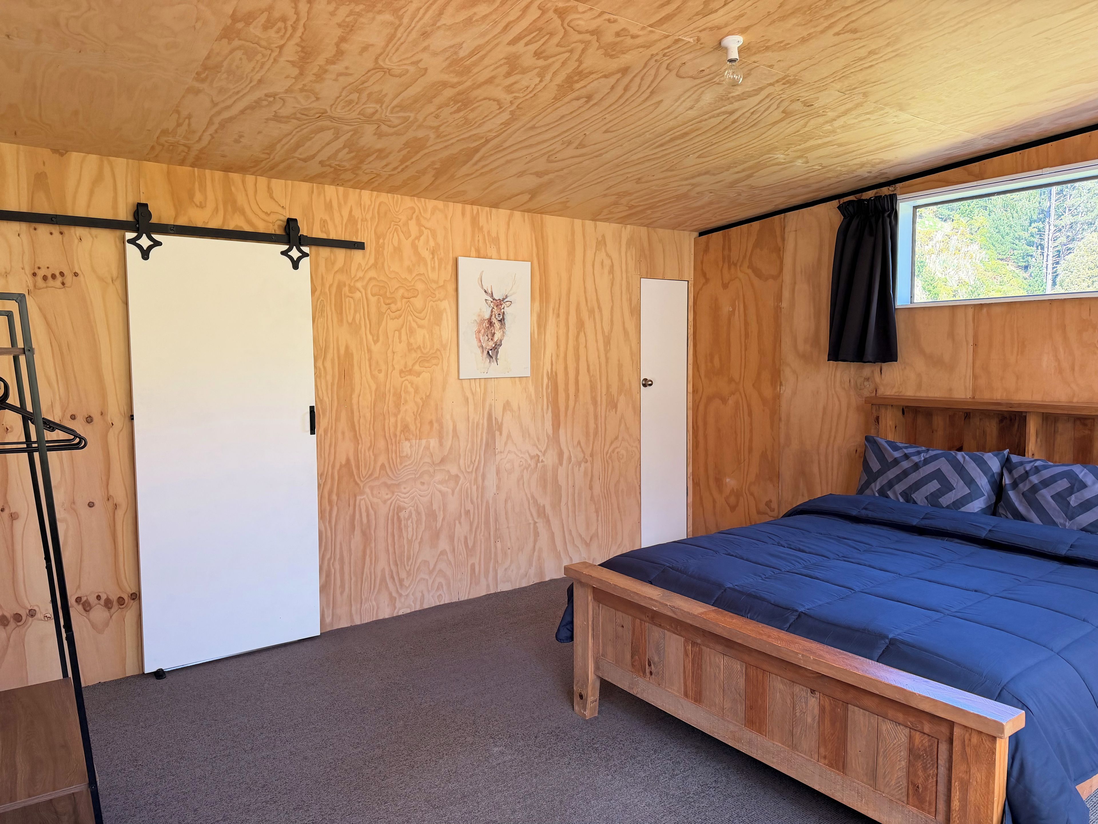 Une pièce avec un lit, un plafond en bois, une porte et une fenêtre.
