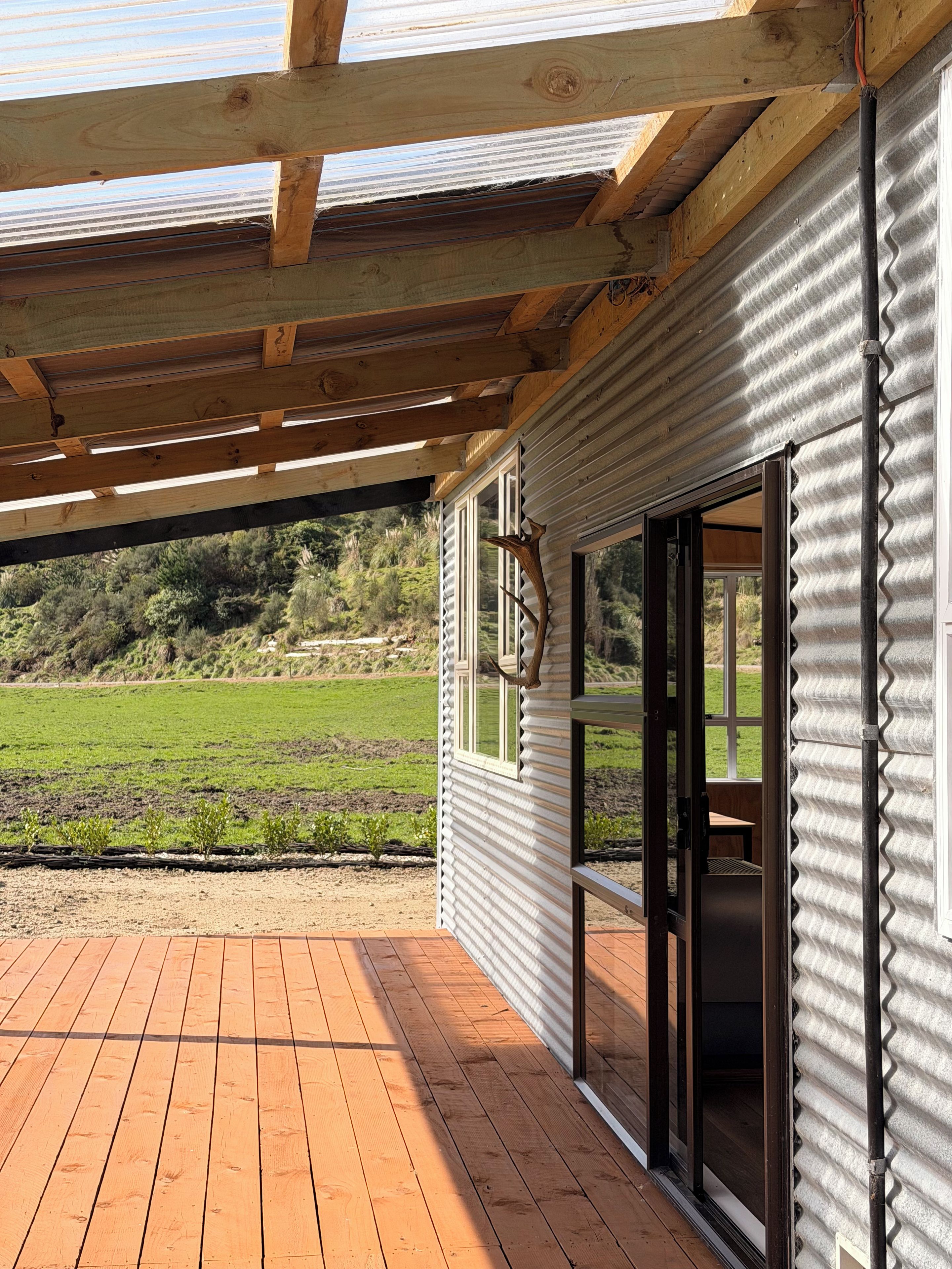 Une terrasse en bois offrant une vue sur un champ verdoyant et des collines.