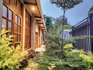 A building with large windows, a covered walkway, and a garden area with various plants.