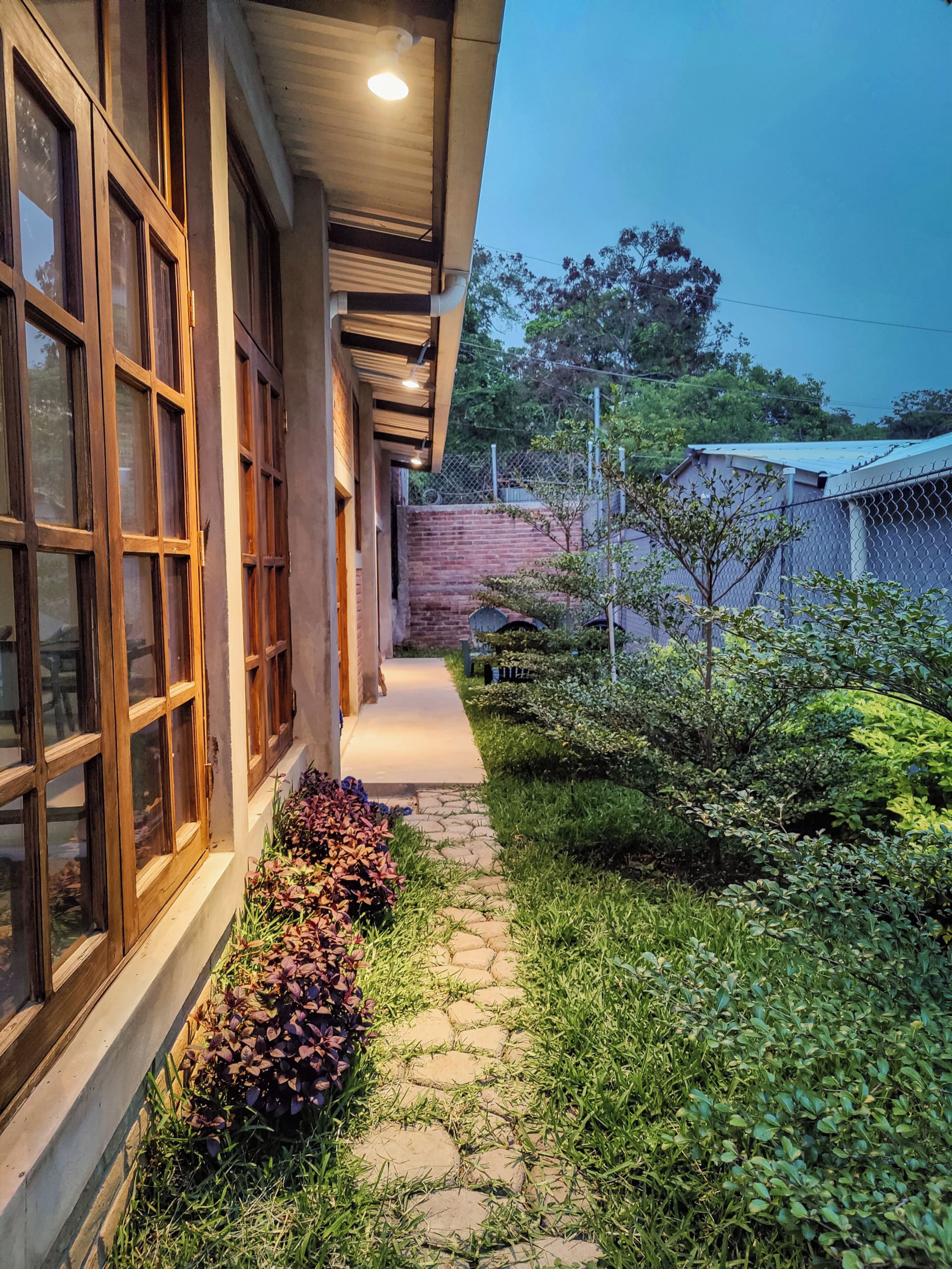 A pathway leading to a building with large windows and a stone pathway.