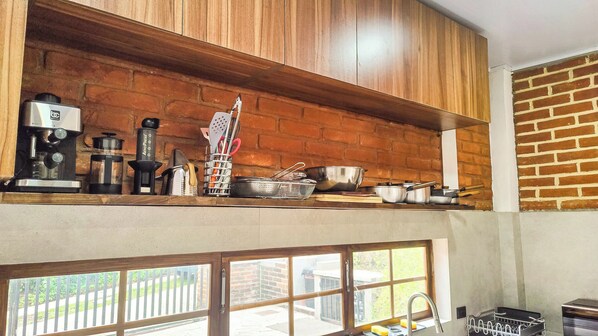 A kitchen with wooden cabinets, a coffee machine, and various kitchen utensils.