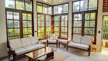 A spacious room with large windows, a sofa set, and a coffee table.
