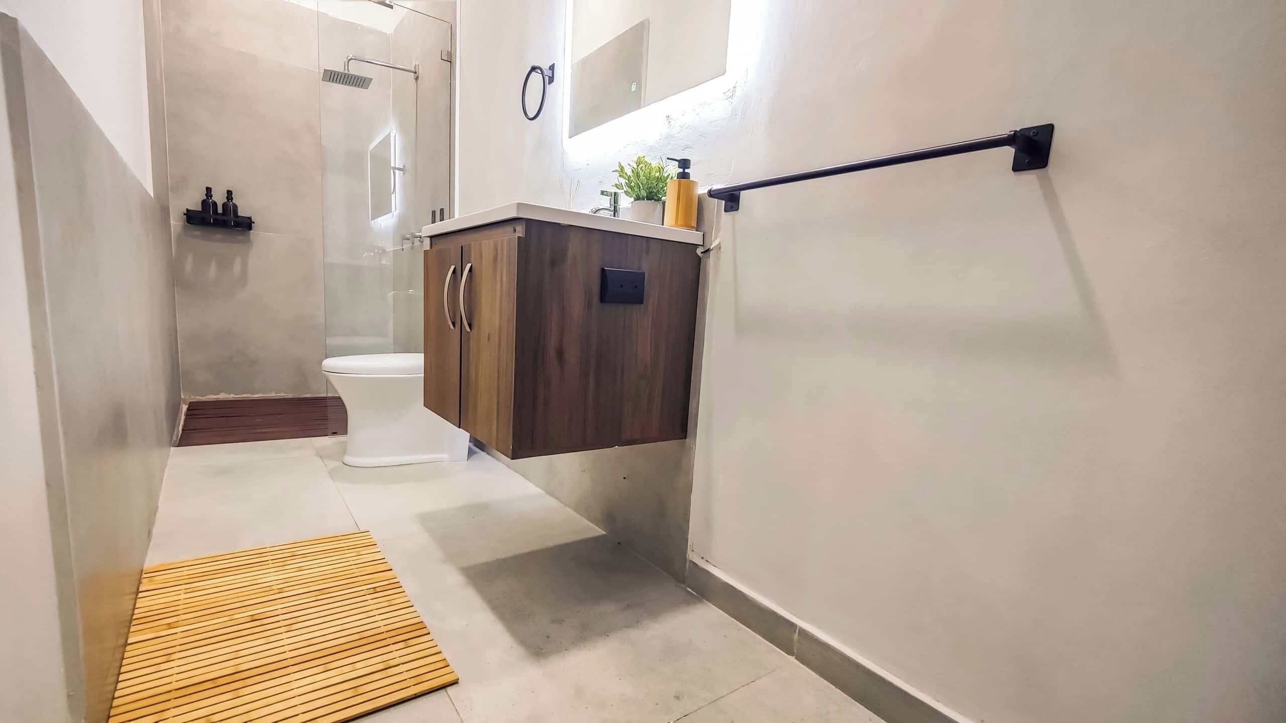 A modern bathroom with a toilet, shower, and wooden vanity.