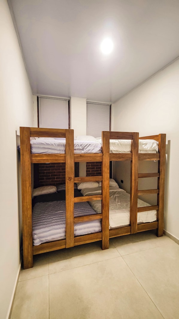 Una habitación con dos literas, una pared de ladrillo y una lámpara en el techo.