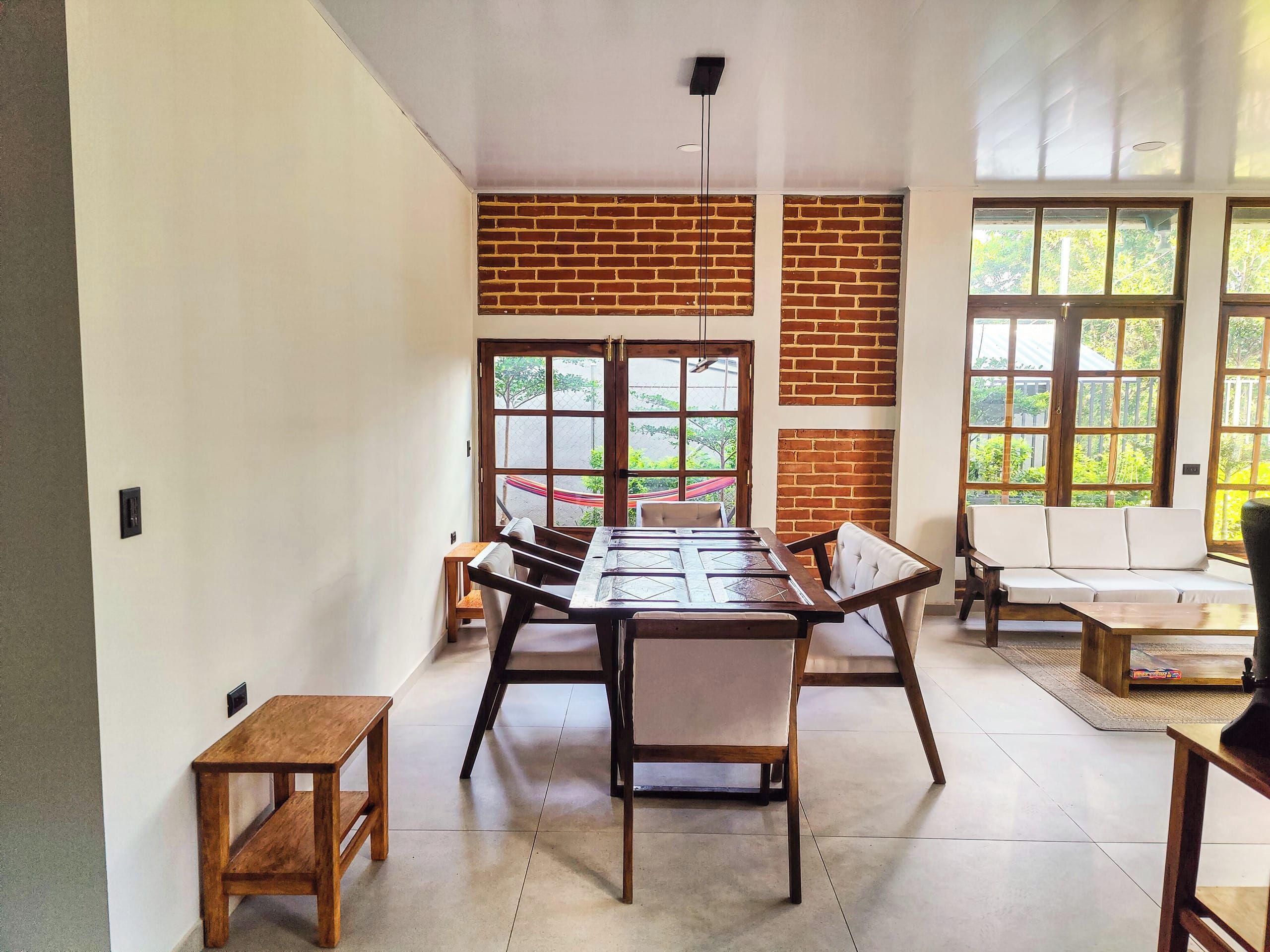 Un espace repas avec une longue table en bois, des chaises et un mur en briques.