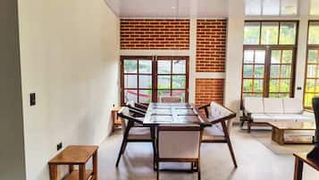 Un espace repas avec une longue table en bois, des chaises et un mur en briques.
