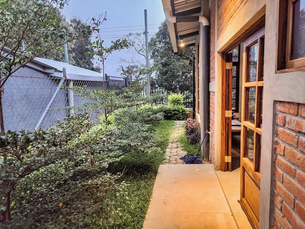 A pathway leading to a building with a brick exterior and a wooden door.
