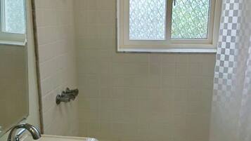 Ein Badezimmer mit einer Badewanne, einem Waschbecken, einem Fenster und einer Duschvorhang.