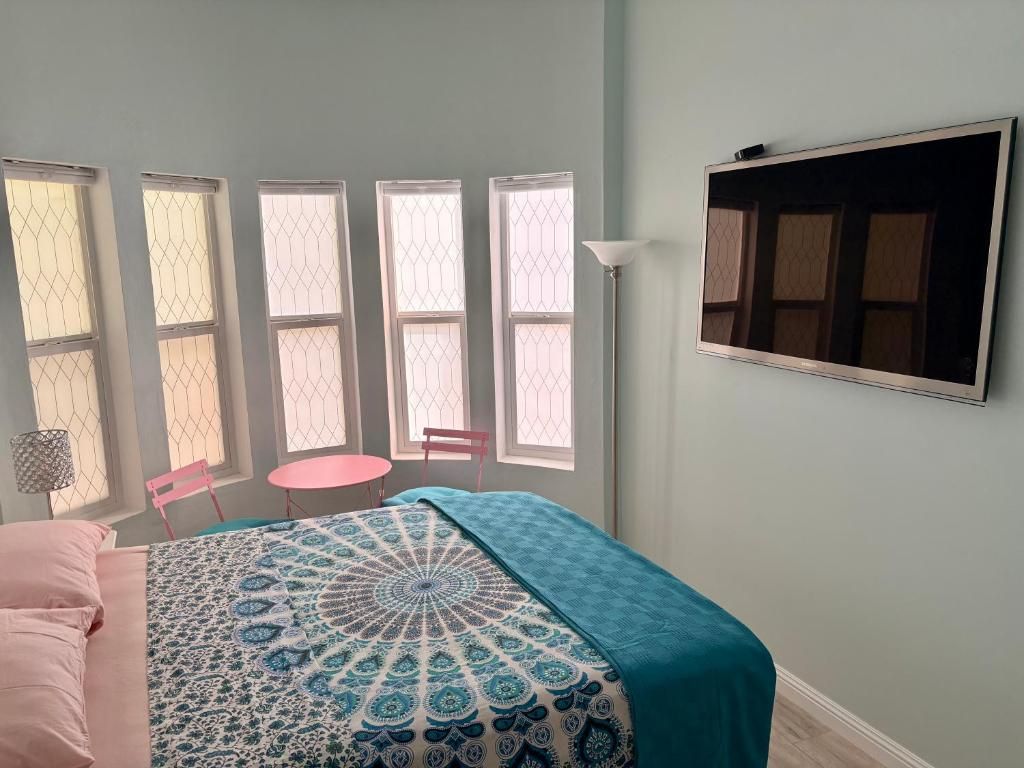 Un dormitorio con cama, una mesa redonda y cuatro ventanas.