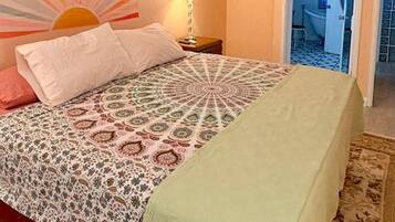Un dormitorio con cama, aire acondicionado de pared, ventana y puerta que da a otra habitación.