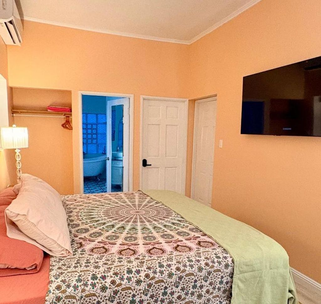 Un dormitorio con cama, televisión y puerta que da a un baño.