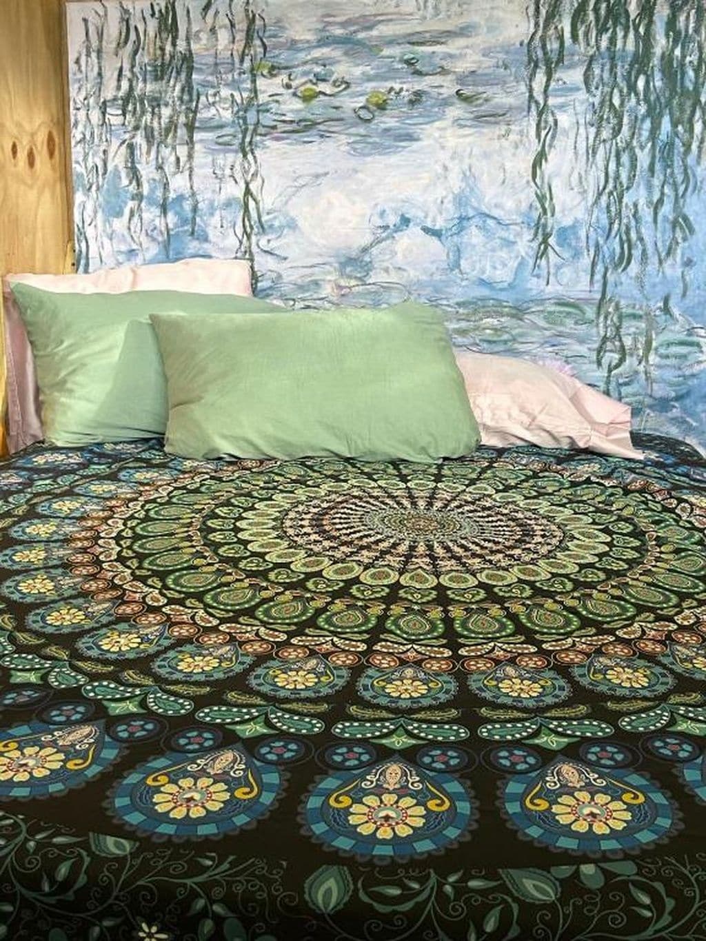 Un lit avec une couvre-lit à motifs, deux oreillers et une fresque murale.