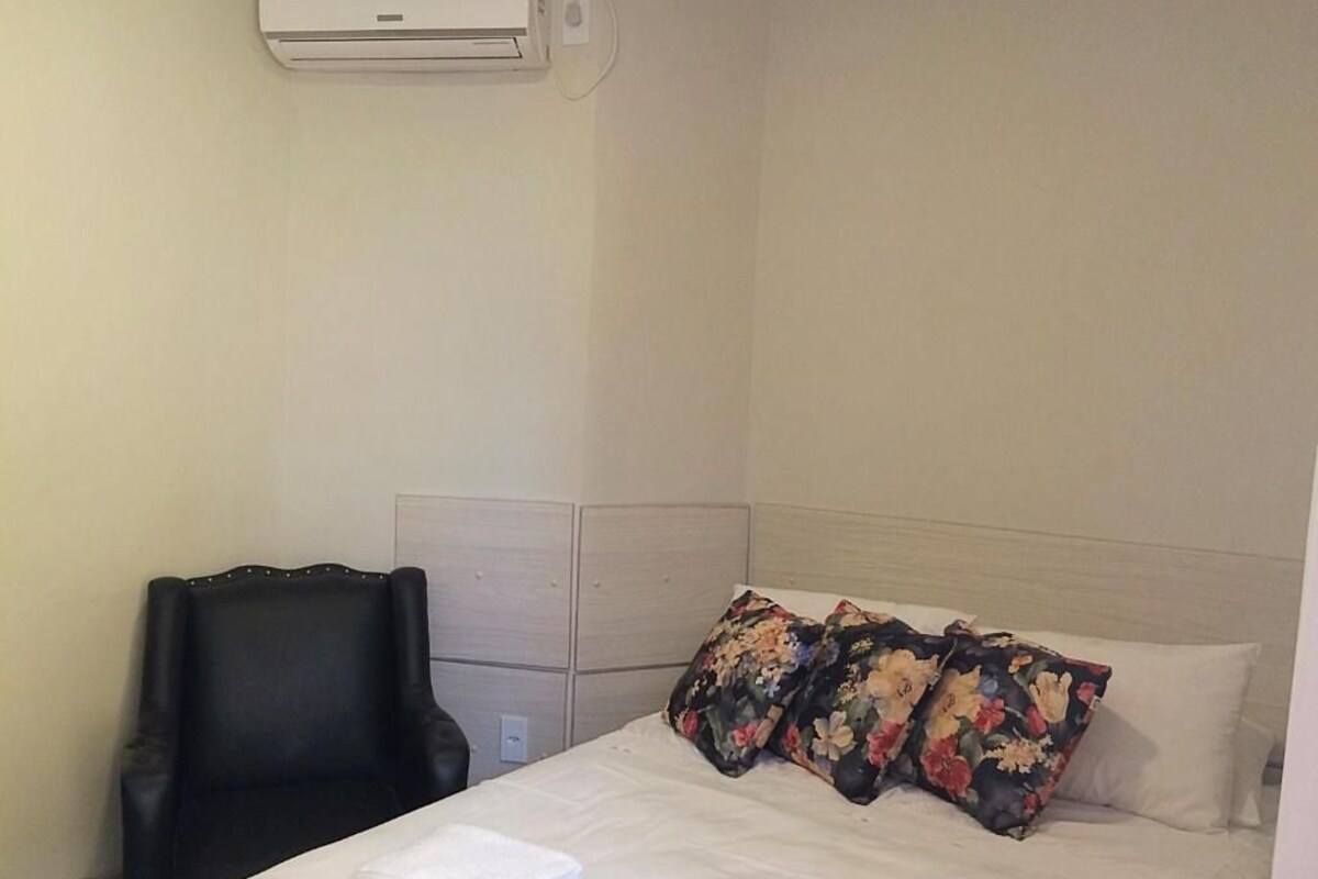 Ein Hotelzimmer mit einem Bett, einem Sessel und einer Klimaanlage.