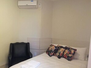 Ein Hotelzimmer mit einem Bett, einem Sessel und einer Klimaanlage.