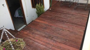 A wooden deck with chairs, a hanging chair, and a small garden area. - O Canto Pousada (Piranhas)