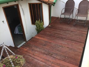 Eine Holzterrasse mit Stühlen, einer Hängematte und einem kleinen Garten.