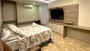A bedroom with a bed, a TV mounted on the wall, and a desk. - O Canto Pousada (Piranhas)