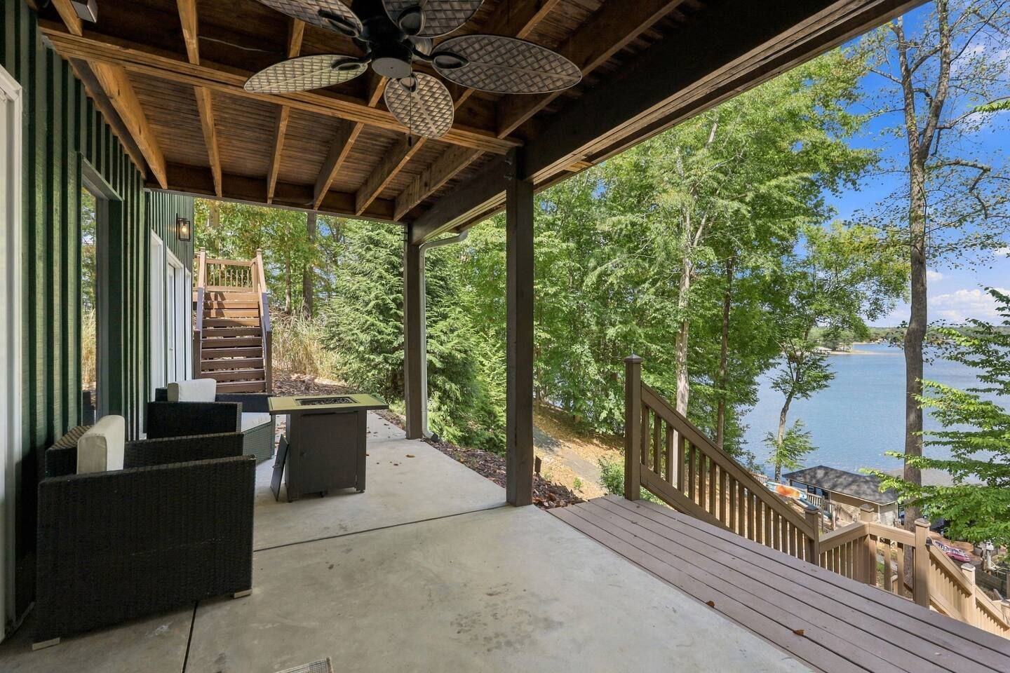 Ein überdachter Außenbereich mit Holzterrasse, integriertem Grill und Seeblick.