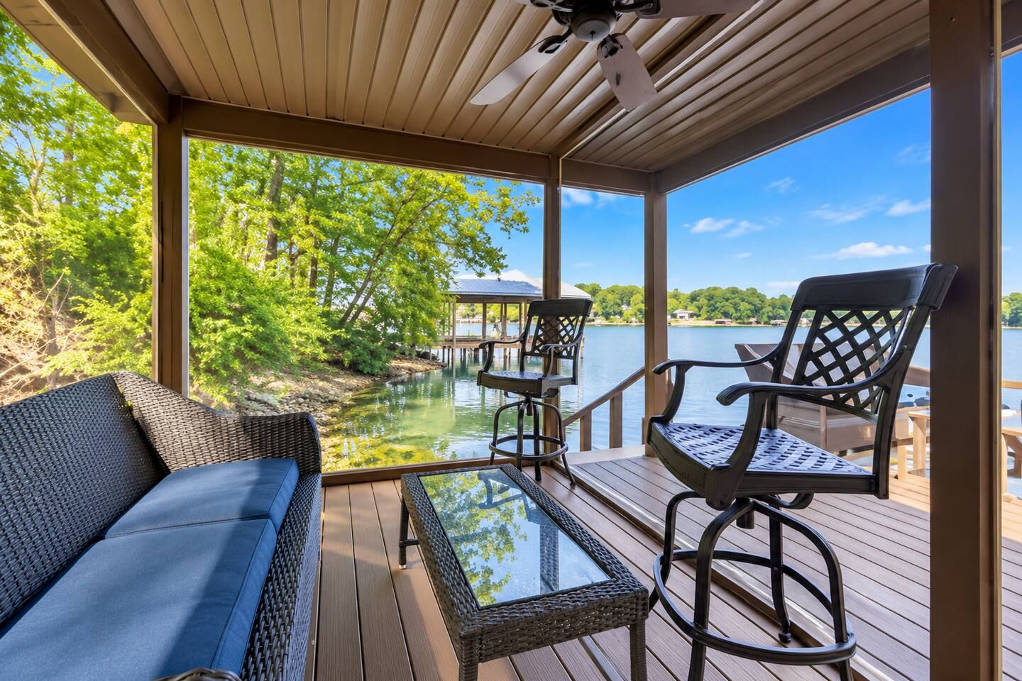 A covered deck with a view of a lake, a dock, and a gazebo.