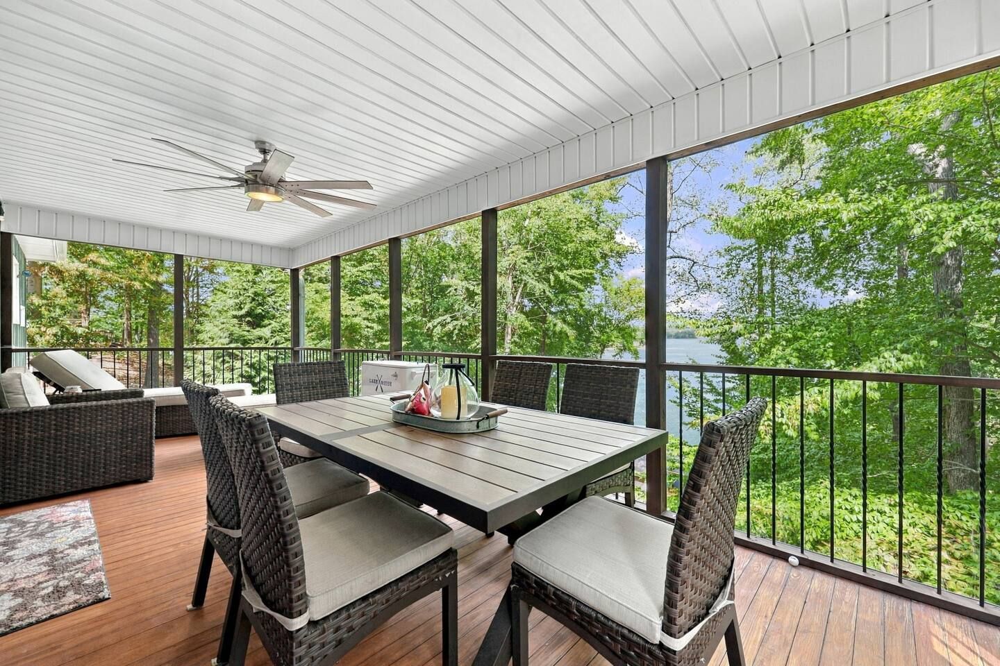 A covered outdoor patio with a table and chairs, overlooking a natural landscape.