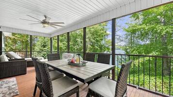 A covered outdoor patio with a table and chairs, overlooking a natural landscape.