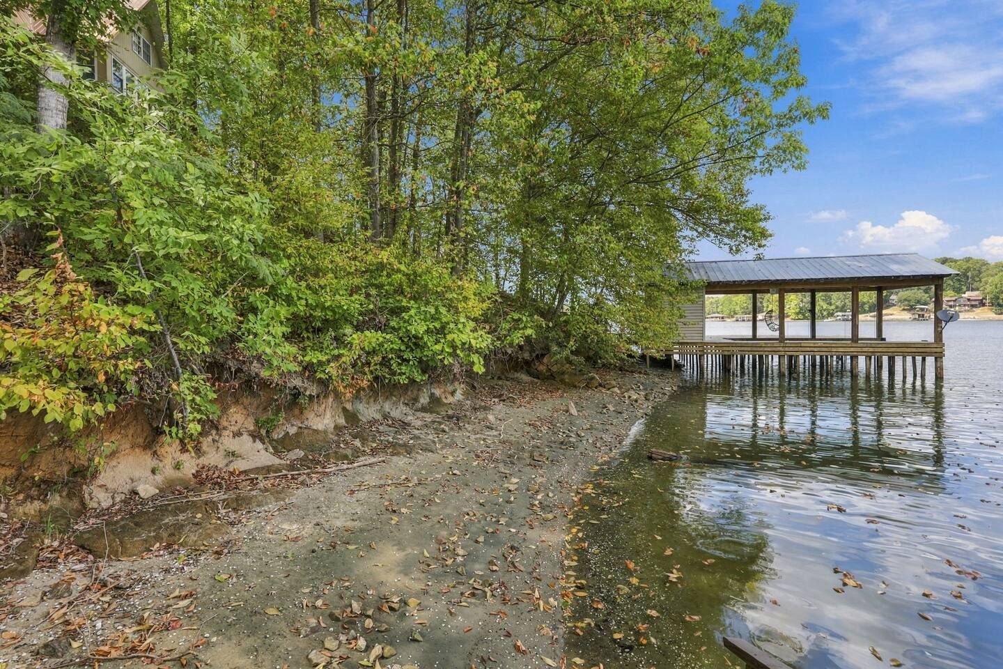 Uitzicht op een rivier met een houten steiger die in het water uitloopt, omgeven door weelderige begroeiing en een gebouw aan de linkerkant.