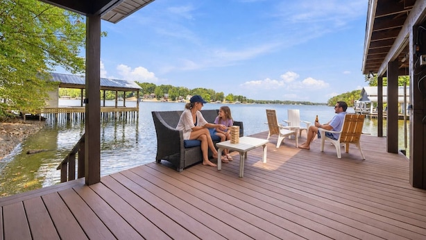 A wooden deck with outdoor seating, overlooking a calm body of water and a dock. - Elevated VIEWS, Outdoorsy Vibe, Speakeasy Kg Suite (Leasburg)