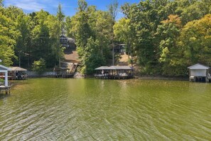 Una propietat a la vora d'un llac amb embarcacions amarrades, una zona d'estar coberta i una estructura de cabana.