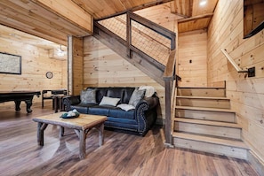 A wooden interior with a sofa, coffee table, and staircase. - Penny's Peaceful Pines (Sevierville)