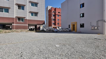 A parking area with multiple cars and a building with a red facade and a yellow door.