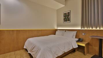A hotel room with a bed, bedside table, and a wall-mounted phone.