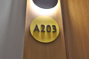 A circular sign with the number 'A203' on a wooden surface.