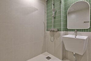 A bathroom with a white sink, a mirror, and a shower with a green tiled wall. - Andong Hotel Coolstay (Andong)