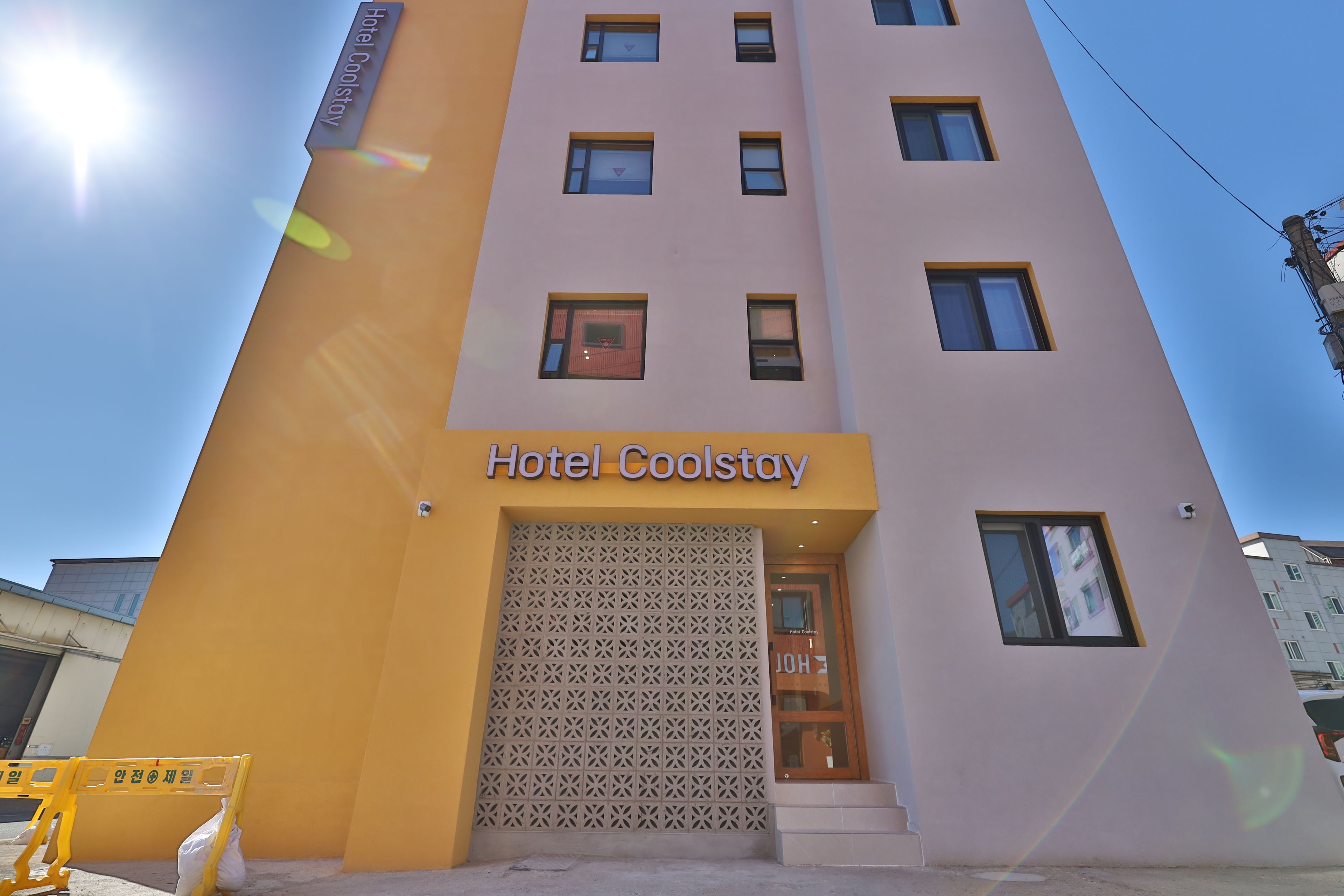 Edificio de hotel con un letrero que dice 'Hotel Coolstay' y una entrada con diseño.