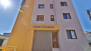 Edificio de hotel con un letrero que dice 'Hotel Coolstay' y una entrada con diseño.