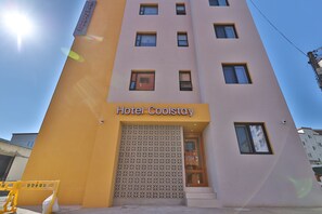 Edificio de hotel con un letrero que dice 'Hotel Coolstay' y una entrada con diseño.