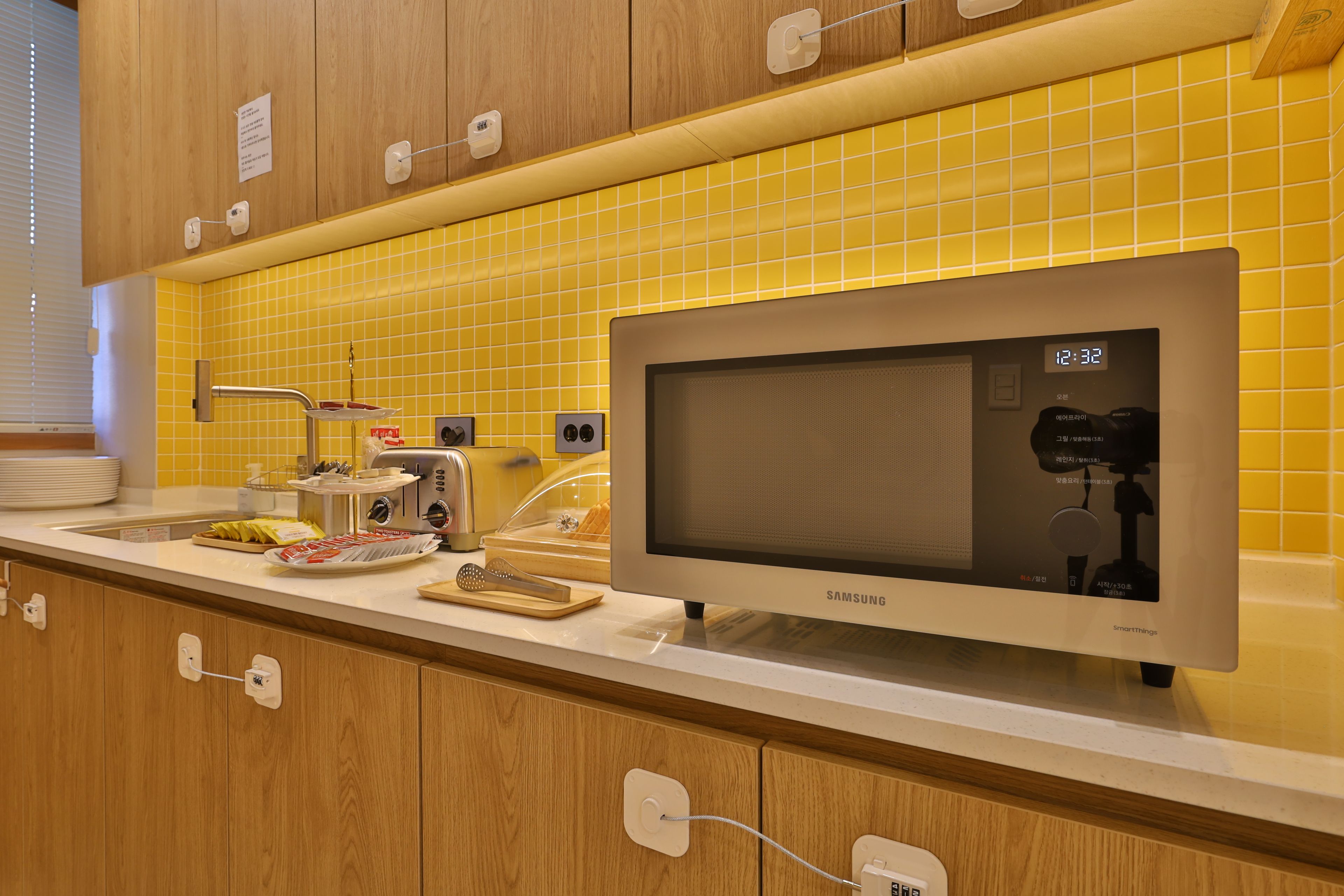 A modern kitchen with a microwave, toaster, and a yellow tiled backsplash.