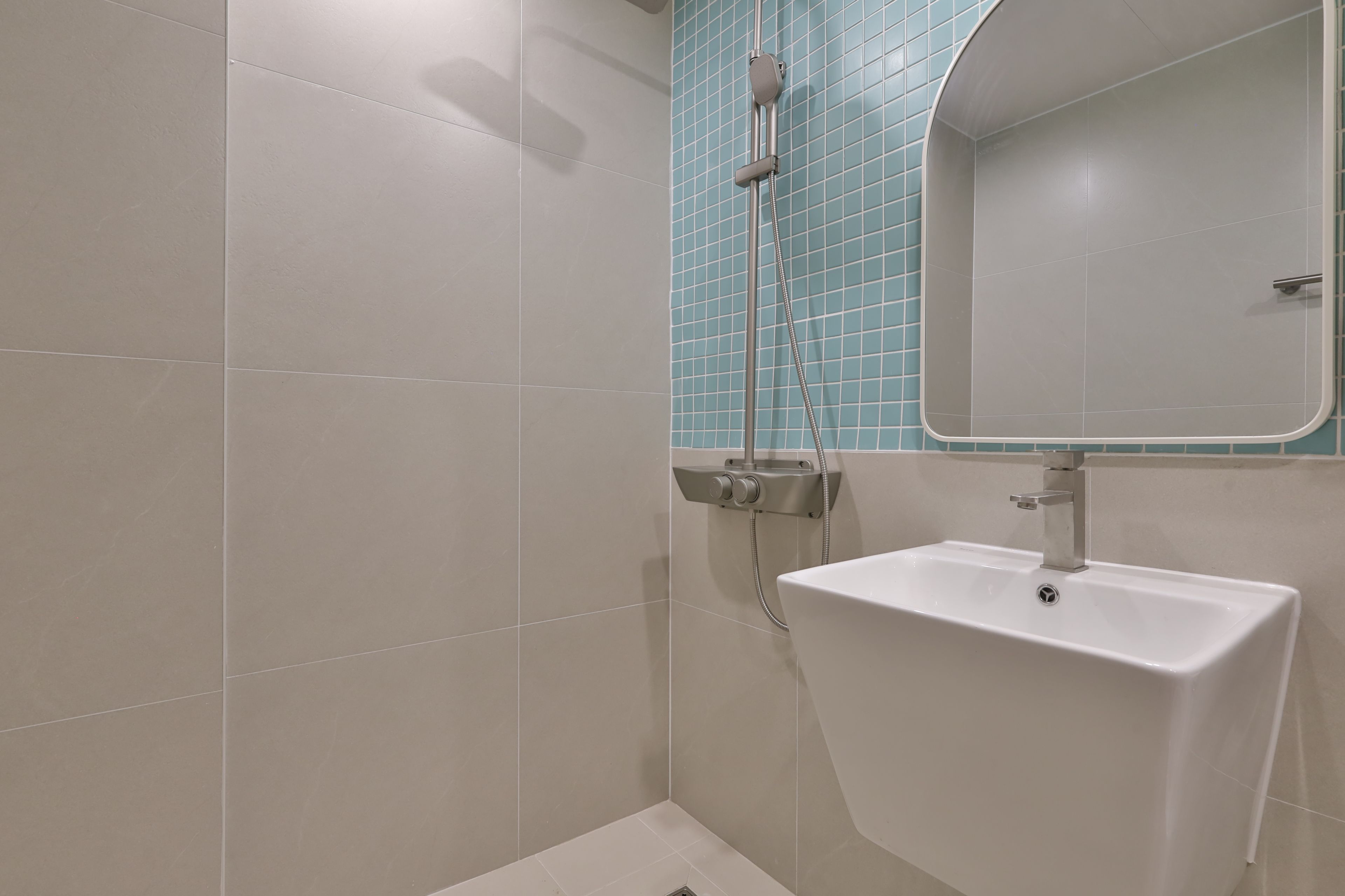 Un baño con ducha, lavamanos y espejo.