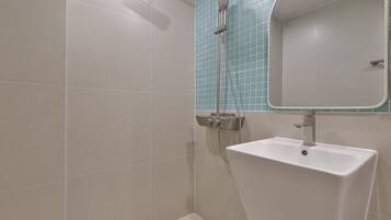 Un baño con ducha, lavamanos y espejo.