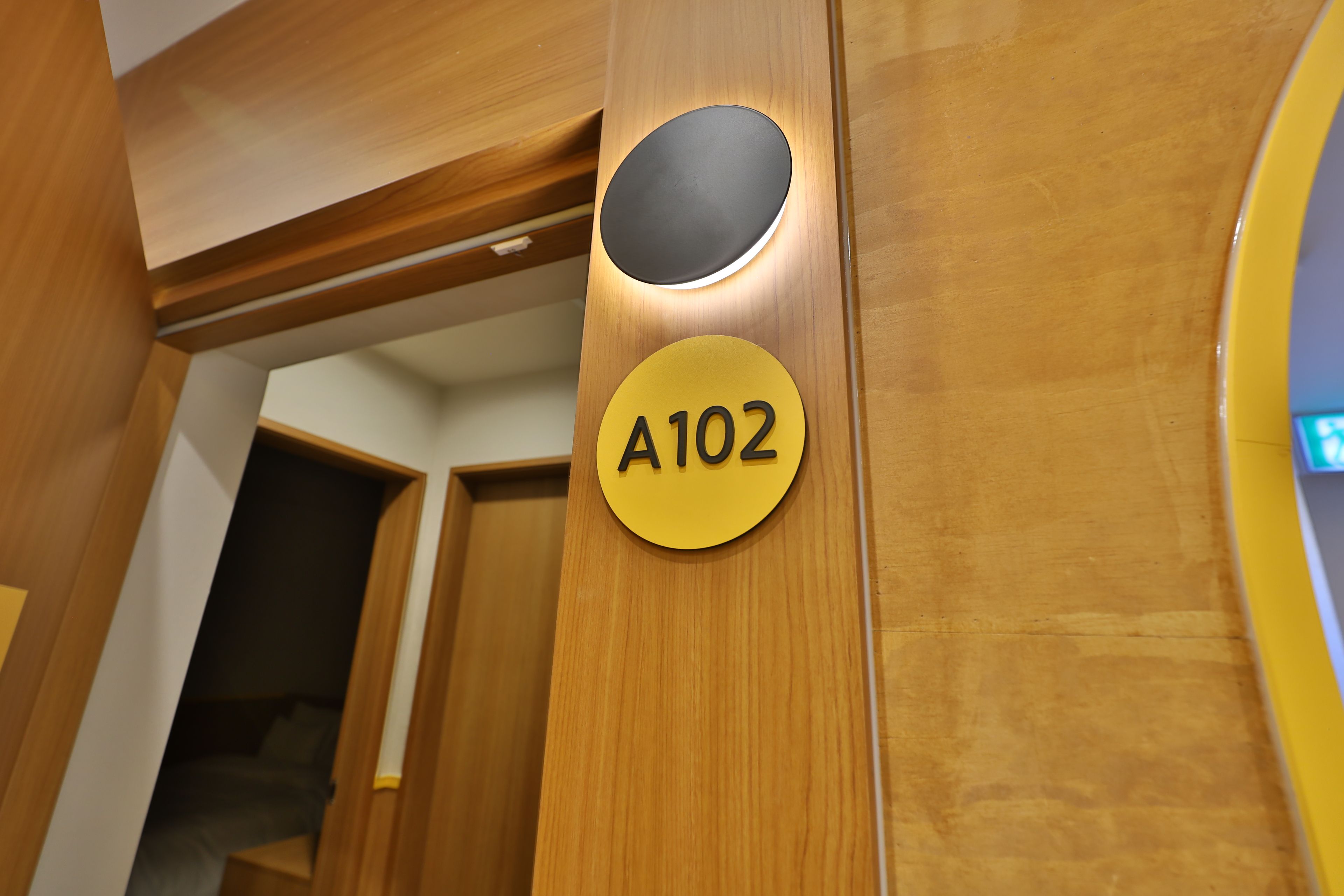 Una puerta de madera con un recorte circular y un letrero amarillo con el número 'A102'.