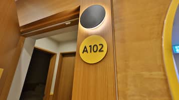 Una puerta de madera con un recorte circular y un letrero amarillo con el número 'A102'.