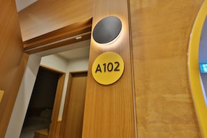 A wooden door with a circular cutout and a yellow sign with the number 'A102' on it.