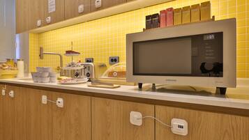 Una cocina con microondas, tostadora y varios utensilios de cocina sobre la encimera.