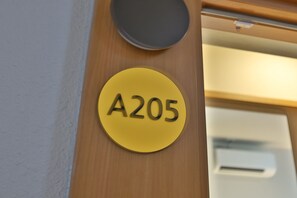 A yellow circular sign with the number 'A205' on a wooden surface.