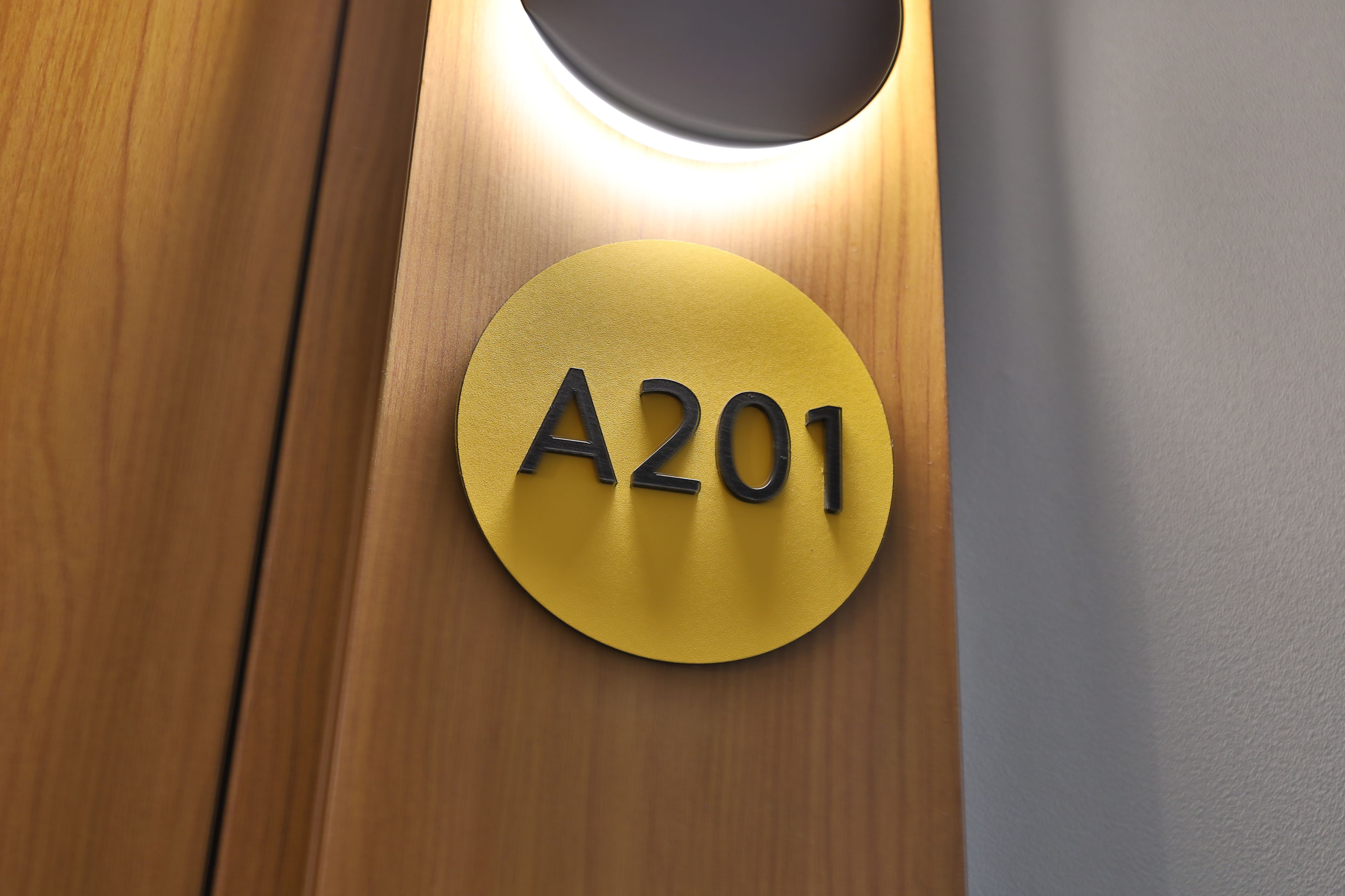 A circular sign with the number 'A201' on a wooden surface.