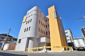 A modern hotel with a unique architectural design, featuring a curved facade and a prominent vertical section.