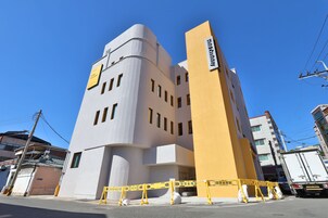 A modern hotel with a unique architectural design, featuring a curved facade and a prominent vertical section.