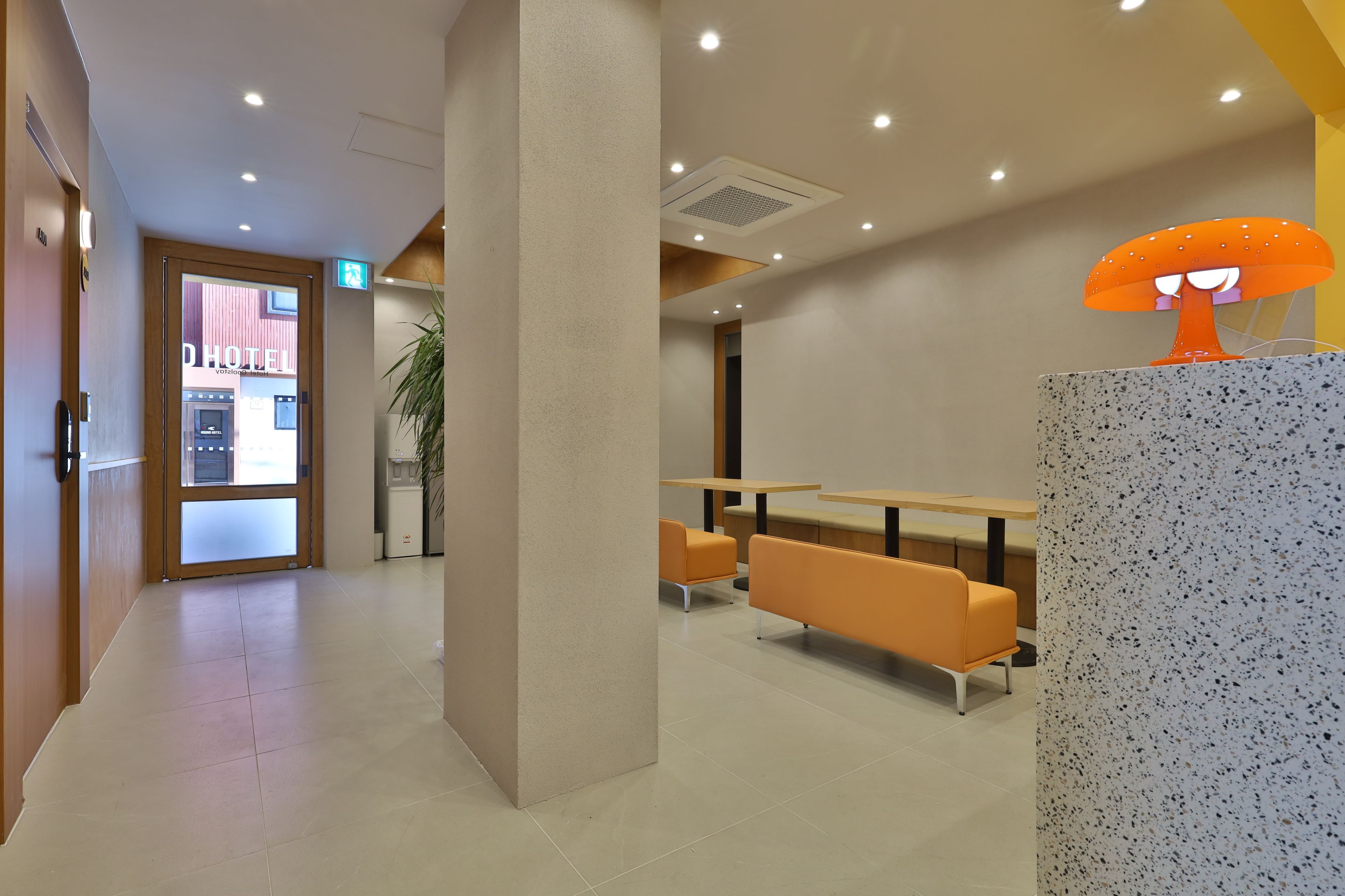A hotel lobby with a reception desk, seating area, and a door leading to the hotel entrance.