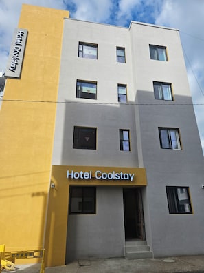 A multi-story hotel building with a sign reading 'Hotel Coolstay.'